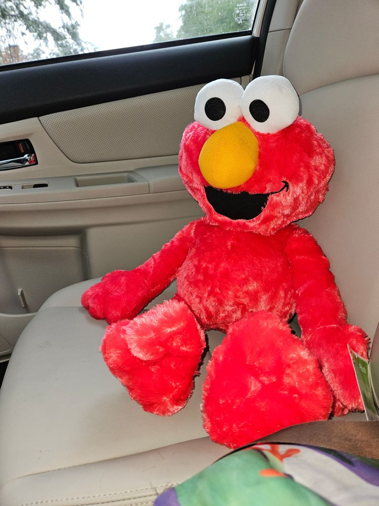 Large plush Elmo toy. Bright red, yellow nose, big eyes. 