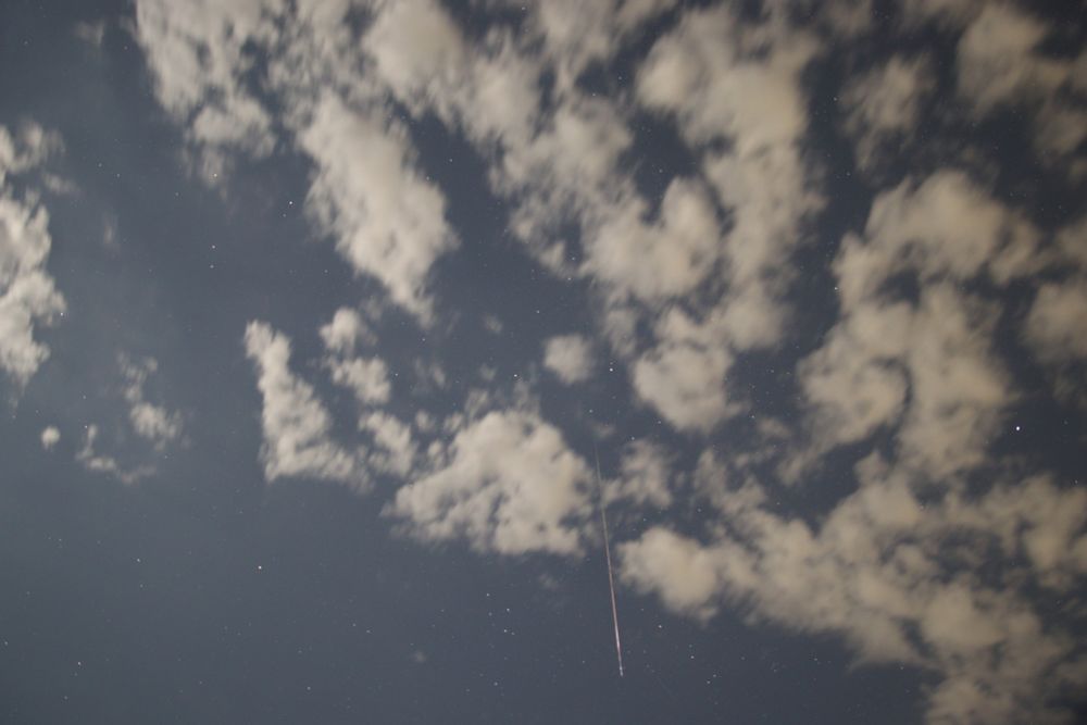 An orange Perseid meteor streaking through some patchy clouds on 13 August 2025 at 02:00 UT. The meteor is between the small constellations of Delphinus and Sagitta. Settings: 10s exp, 16mm fl, f/2.0, ISO-800.