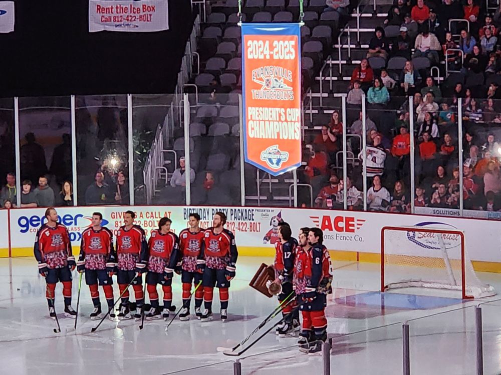 Evansville Thunderbolts players from last season with the President's Cup in front of the goal and beneath the championship banner
