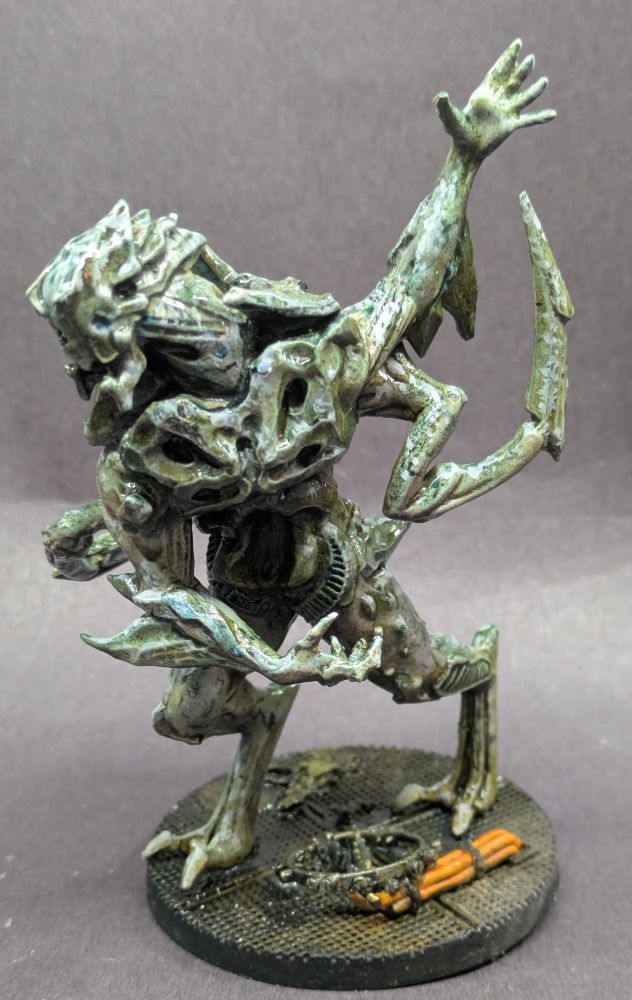 An imposing model of an alien with claw reared back to strike. Broken greasy machine parts and wires lay upon the rusted grating he walks over.