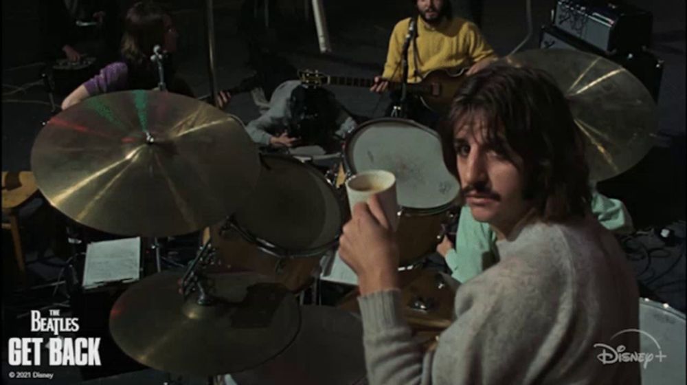 a poster for the beatles get back shows a man drinking coffee