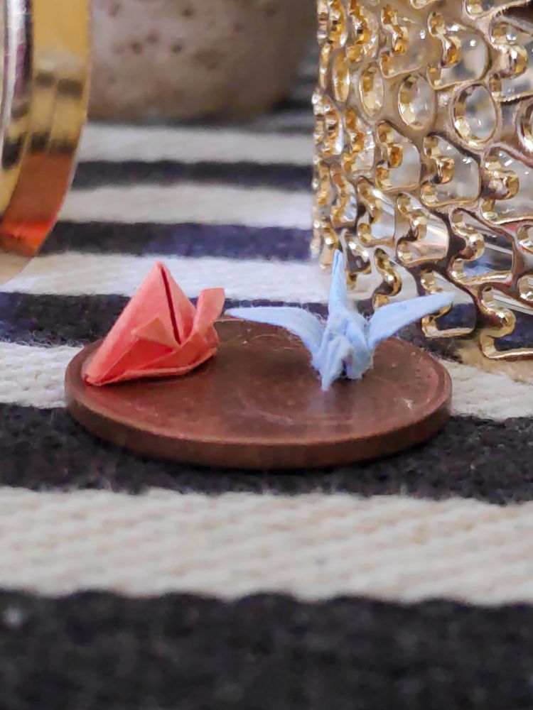 Two origamis (crane & hat) top of 5 cent coin.
