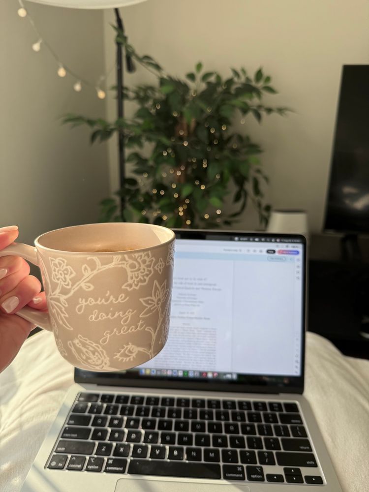 A cup that says “you’re doing great” in front of a laptop