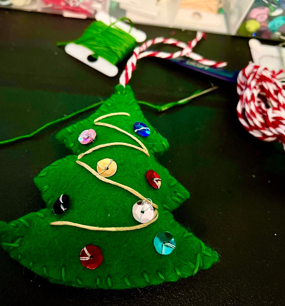 A poorly stitched felt tree with ornaments for sequins and a little gold thread zig zagging to represent garland. 
