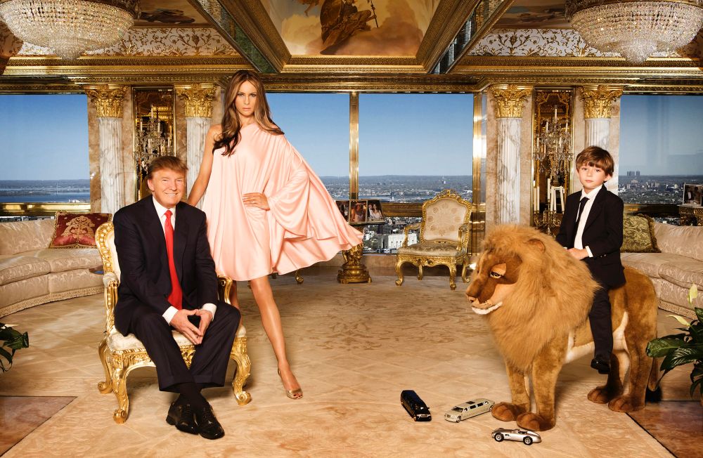 Donald Trump, Melania Trump and their son Barron Trump pose for a portrait in a gaudy NYC penthouse. There is gold gilding everywhere and Barron is on a large lion toy thing. 