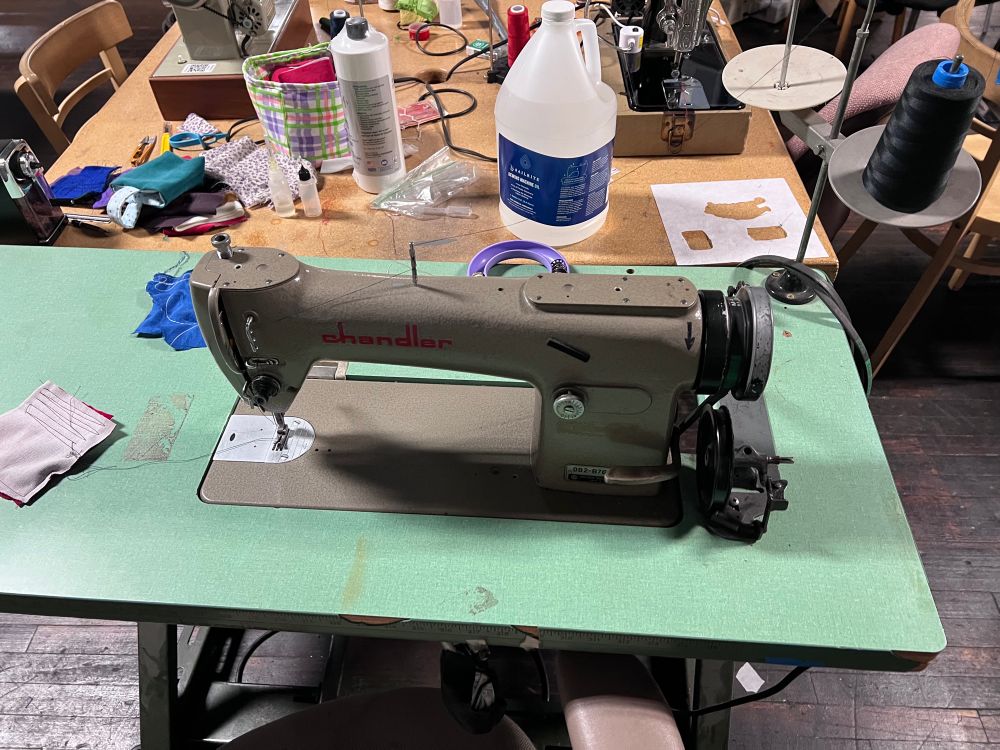 A photo of an old sewing machine, on a table of five.