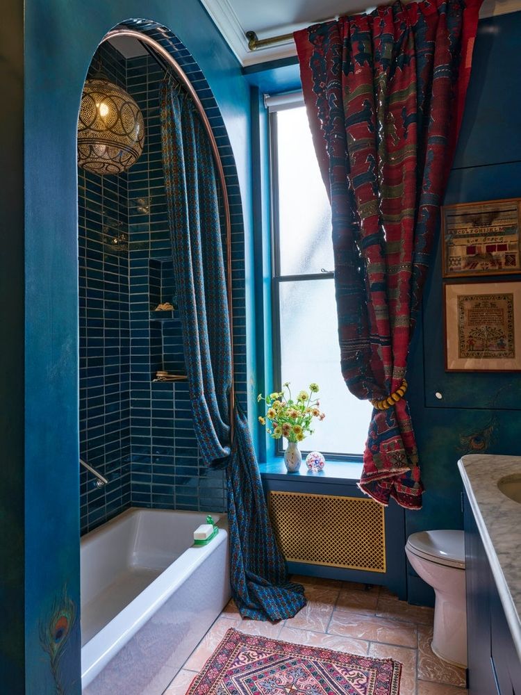 A vintage Moroccan pendant light illuminates the Clé tile-clad shower nook in the primary bath. Shower curtain in a fabric from Una Malan; walls in a custom color by Sydney Harbour Paint Co.; rug from Nazmiyal Collection.