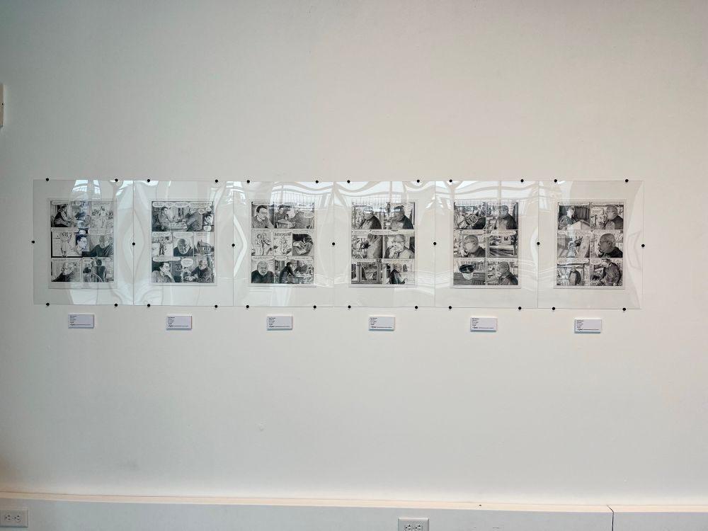 Framed original comics pages by Karl Stevens hung on a gallery wall