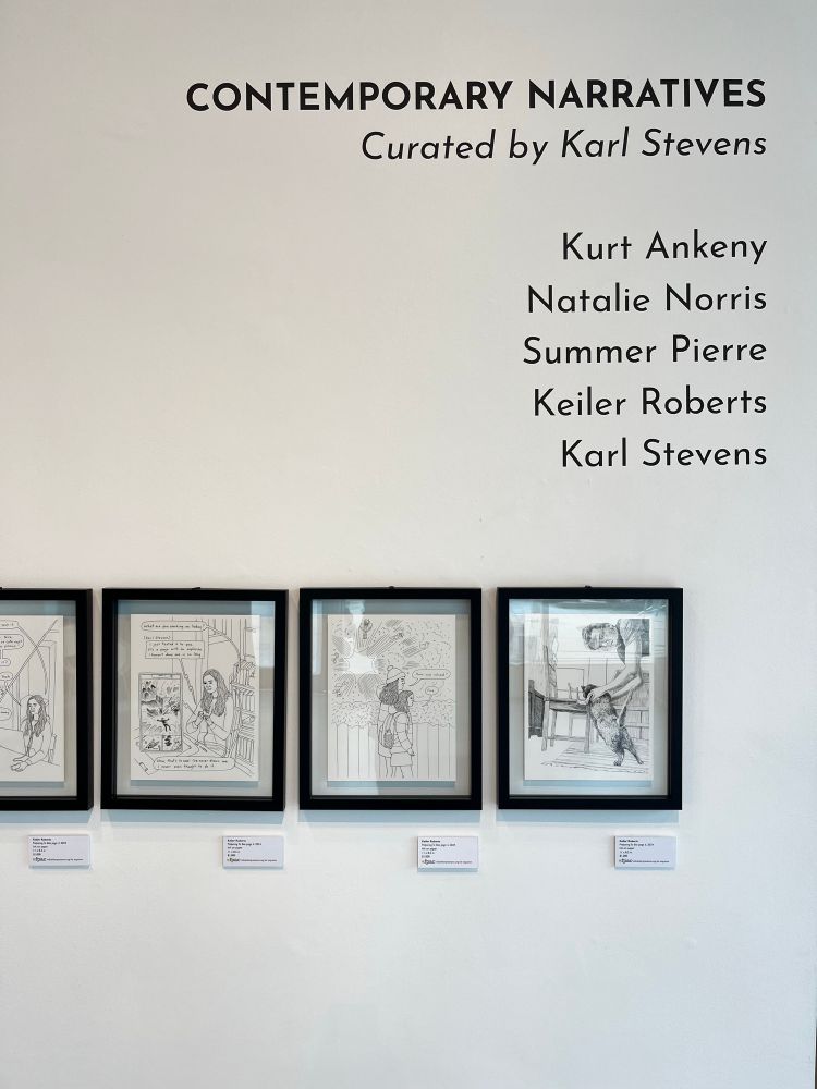 Framed original comics pages hung on a gallery wall below wall text with the title “Contemporary Narratives” and the names of the participating artists: Kurt Ankeny, Natalie Norris, Summer Pierre, and Karl Stevens.
