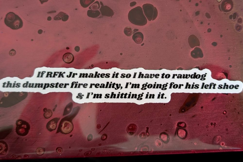 A white sticker with black text that reads, "If RFK Jr makes it so I have to rawdog this dumpster fire reality, I'm going for his left shoe & I'm shitting in it."