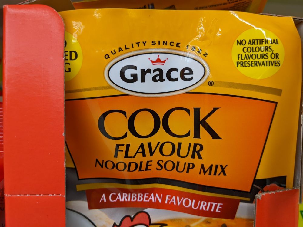 Picture of a ramen noodle soup packet labeled "Cock Flavor Noodle Soup Mix. A Caribbean favorite."