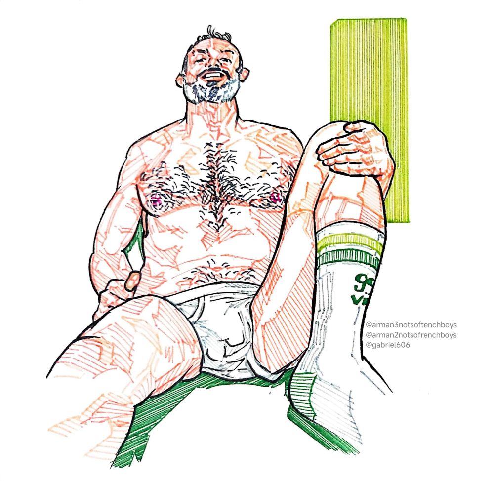 Model in his underwear wearing long socks with some green stripes on his feet sits on the floor smiling at the viewer. The model's shadow and the light on the wall are green colored