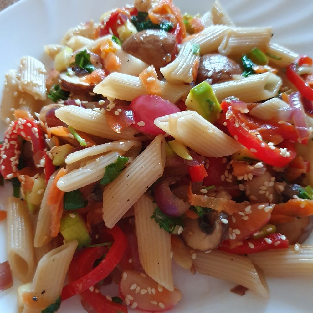 Bunter Nudelsalat, mit Blattspinat, rotem Paprika, Karottenraspel, Radieschenviertel, Champignons, Zucchiniwürfel und Sesamsamentopping