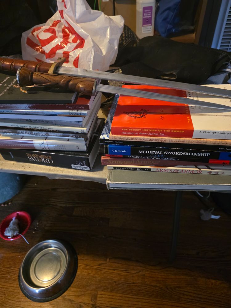 two stacks of books with a sword and dagger on top