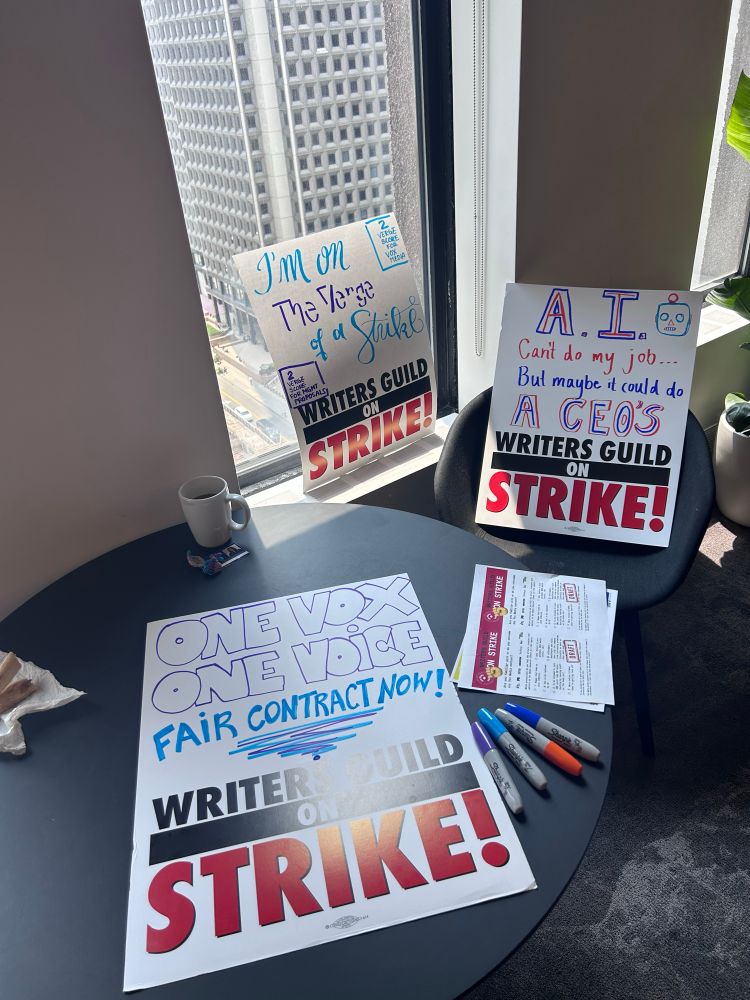 Various handmade picket signs against an office window. 