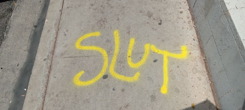 Someone spray painted "slut" on the sidewalk