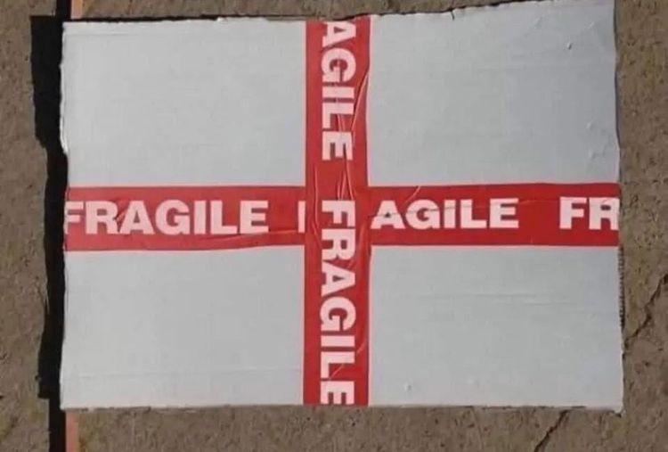 Red parcel tape crossing a while parcel with FRAGILE written on it 