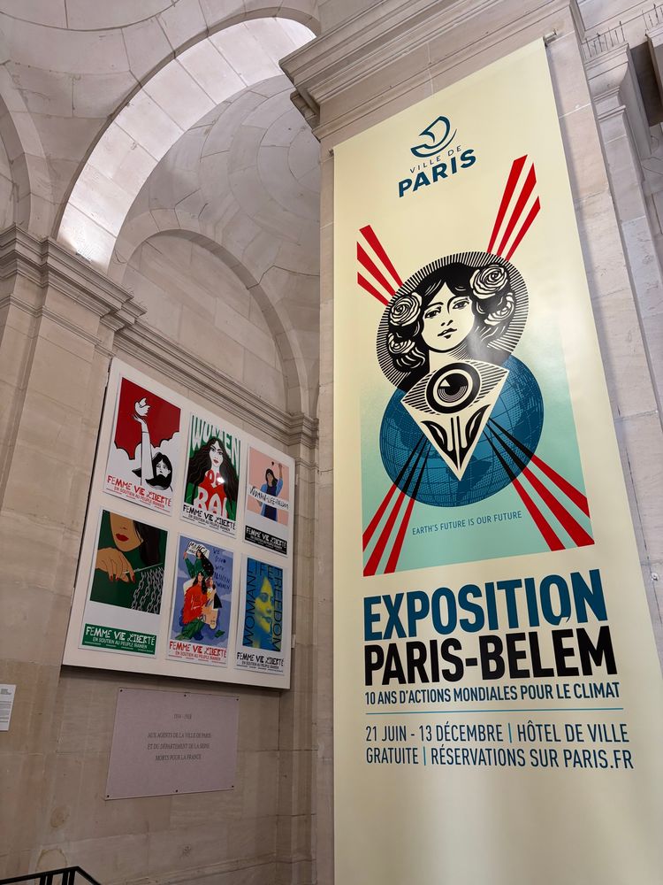A banner hanging on a column at the entrance to the exhibition. Beneath the artwork, it says “Exposition Paris-Belem: 10 and d-actions mondiales pour le climat.”