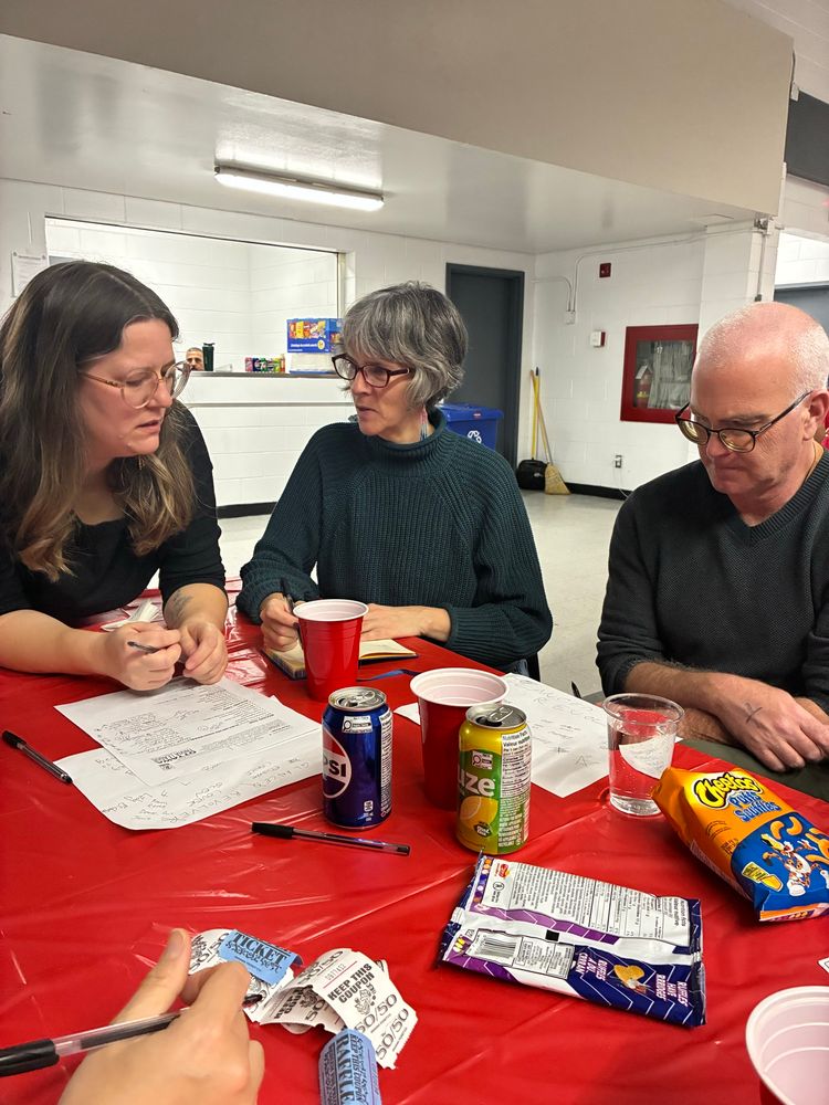 Jeff and two other people at a table, concentrating on trivia questions 