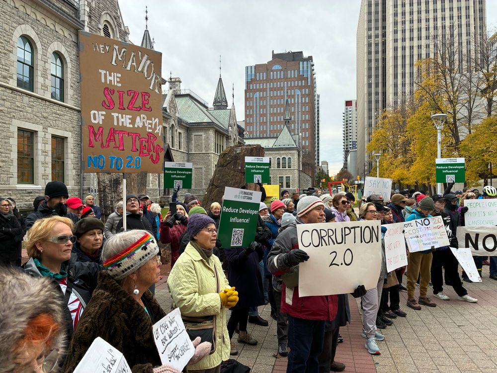 Crowd at the rally. One sign says: Mayor, the size of the stadium matters. 
