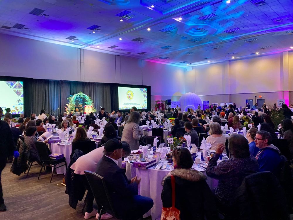 People at tables with white table cloths at a gala