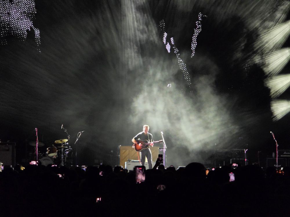 Ben Gibbard playing a guitar on stage