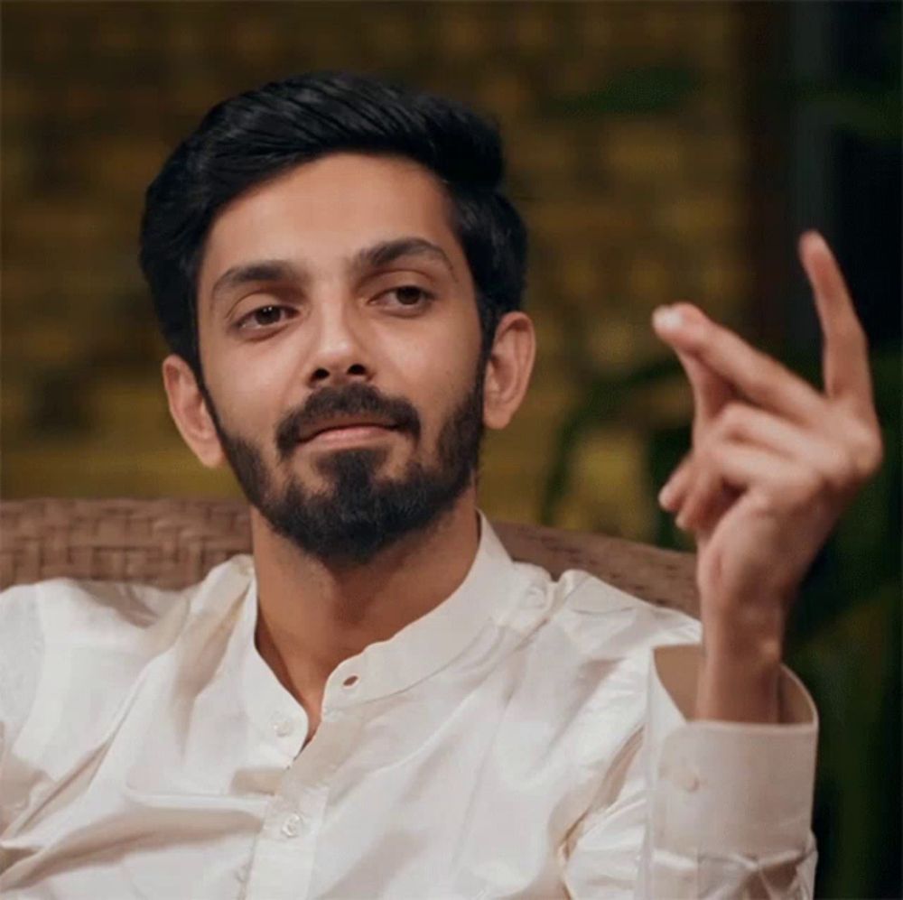 a man with a beard wearing a white shirt is making a gesture with his hand