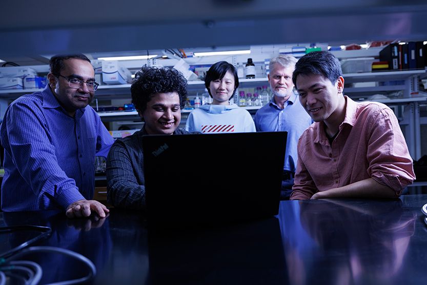 a group of people inside of a lab, huddled around a computer