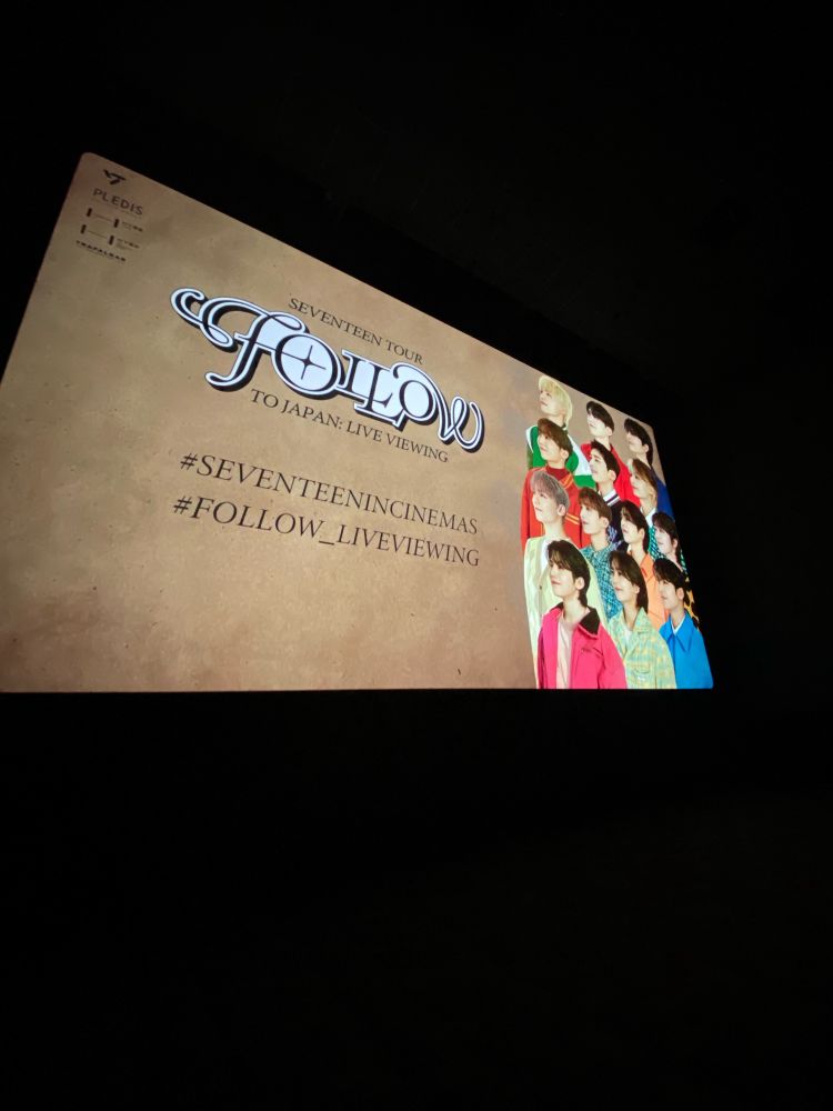 SEVENTEEN, the kpop group, Follow to Japan tour poster on screen. Includes all the members grouped on the right side showing their side profiles.