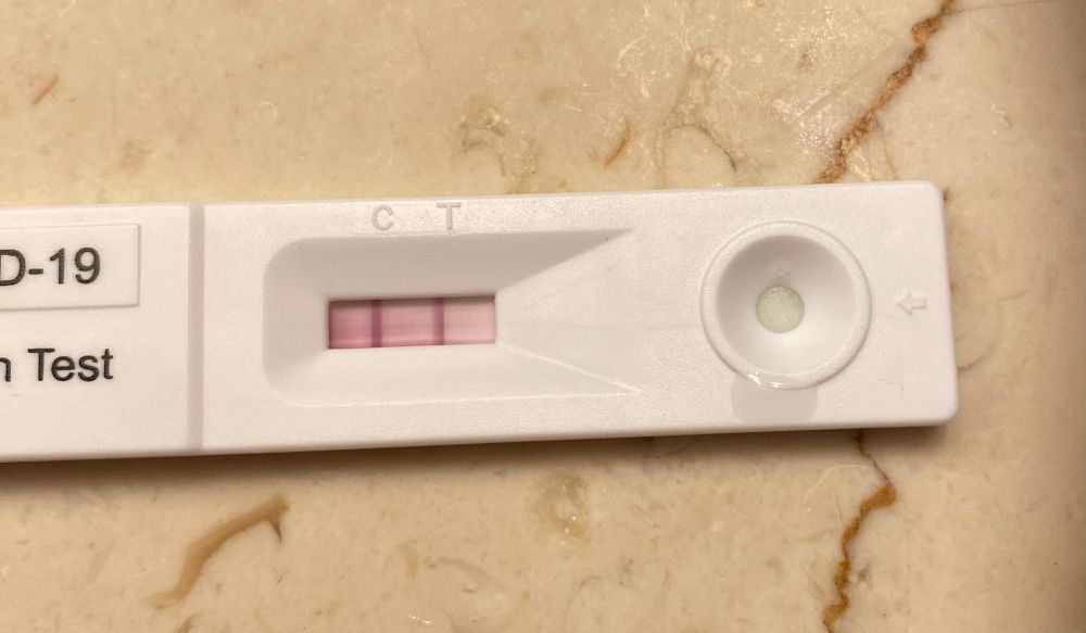A positive covid test sitting on a marble bathroom counter top. Ugh 😩 