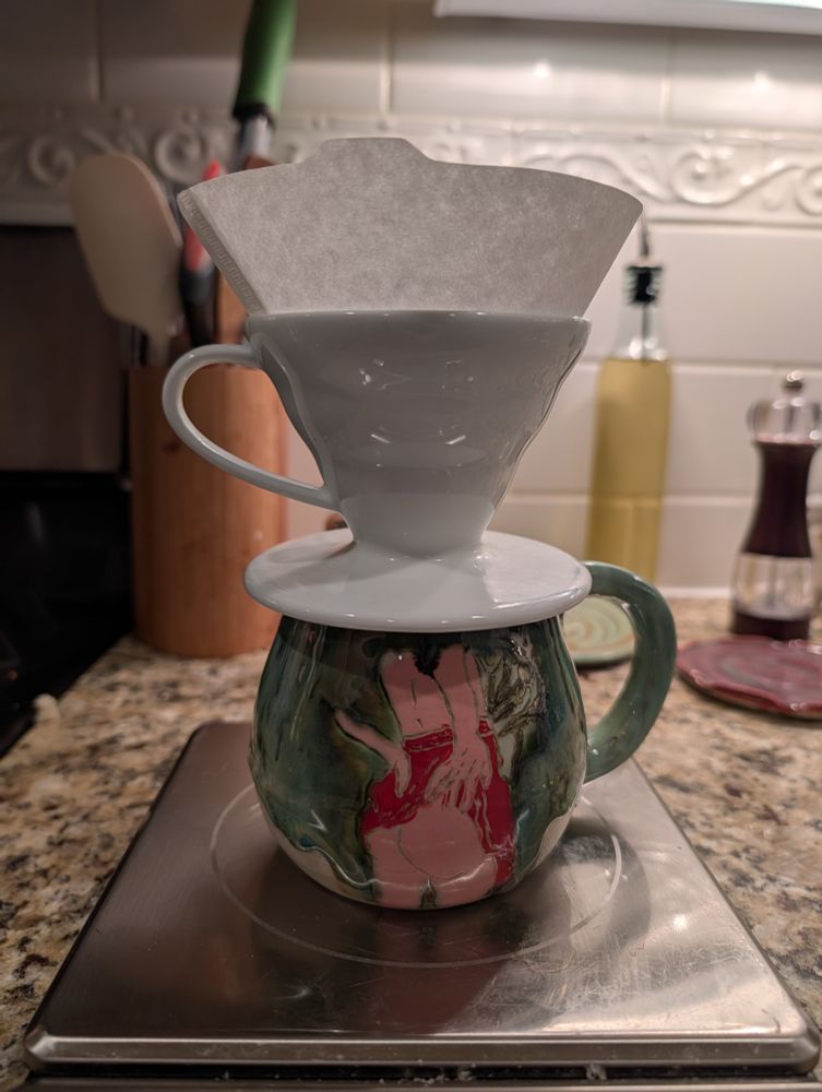 Coffee pour over preparation featuring a mug with a woman pulling up her skirt showing her bare ass