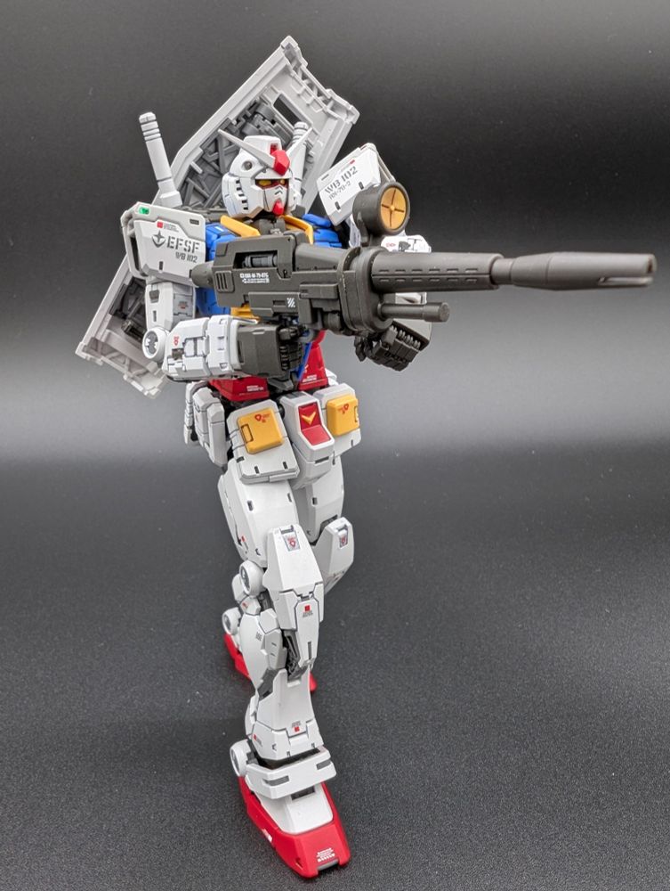 Side profile of the RX-78-2 aiming a beam rifle with two hands and shield on its back.
