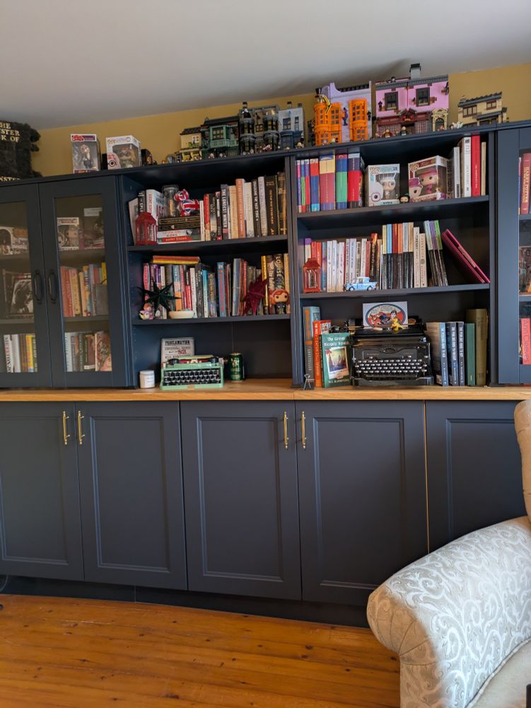 Blue bookcase and cabinets with a book collection displayed. 
