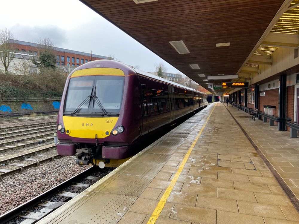 EMR purple livery 170507 at Leicester platform
4 with headlights lit. You can see salt along the
Platform due to the cold weather. A passenger walks alway from the train. The sky is grey.