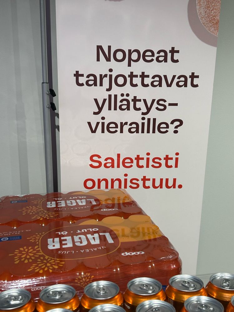 Salen mainoskyltti: ”nopeat tarjottavat yllätysvieraille?” Alle pinottu Coop lagerlaatikoita