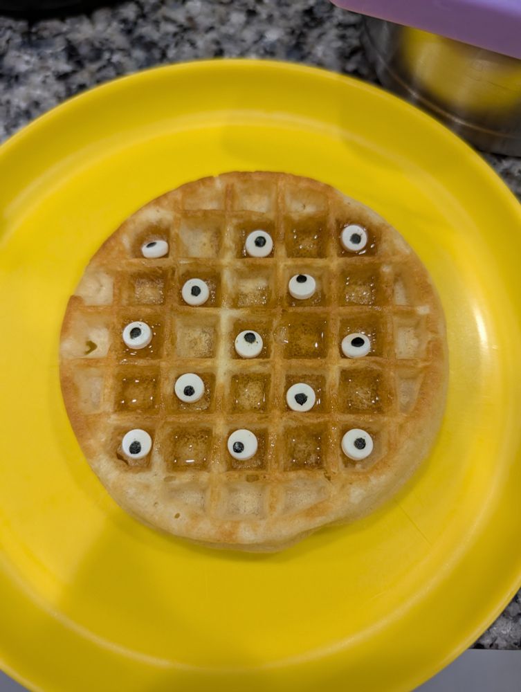 Eggo waffle with syrup and eyeball sprinkles in alternating squares on a yellow plate