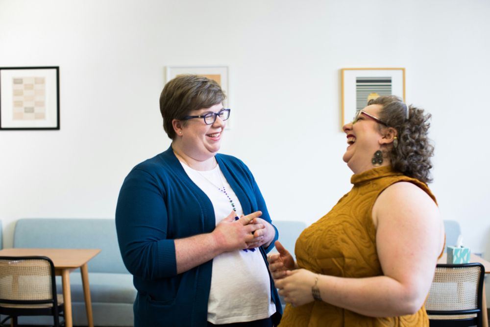 Zum Welt-Adipositas-Tag: Zwei lachende übergewichtige Frauen wenden sich einander zu. (c) Unsplash/allgo-an-app-for-plus-size-people