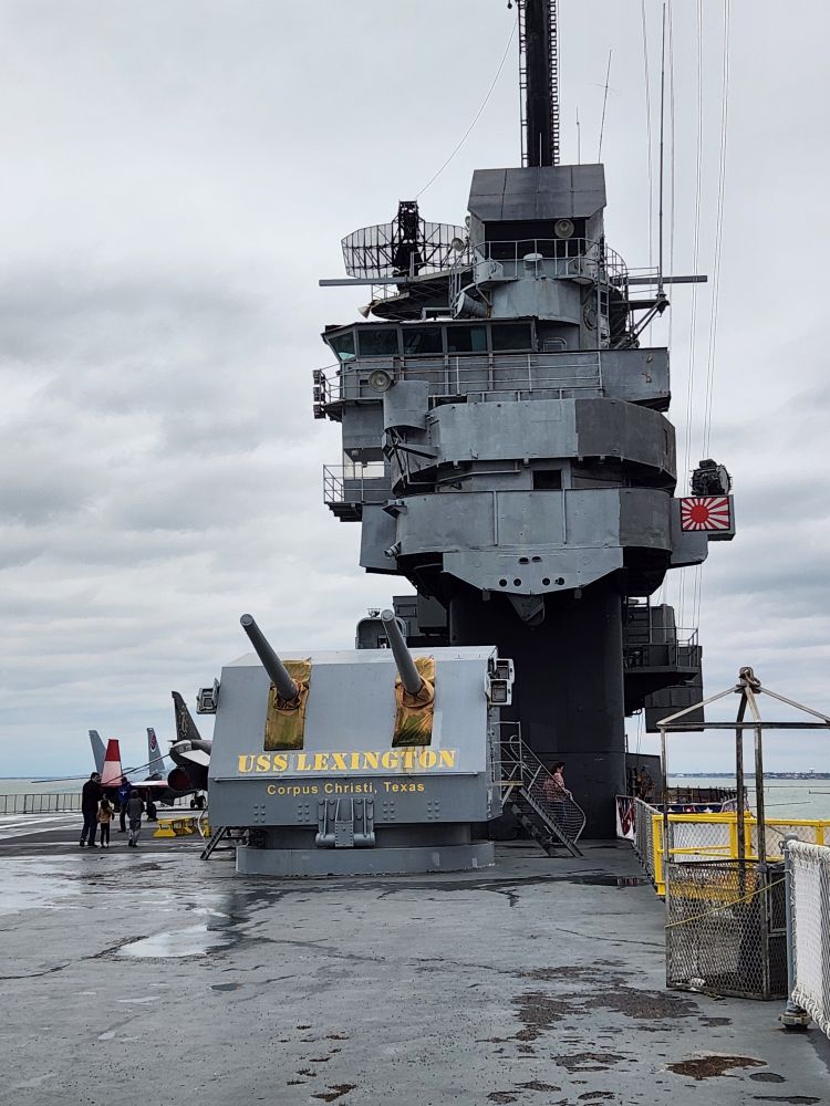 View of the island section of the USS Lexington. The island includes the air directors view of aircraft landing. A IJN flag is on the right side indicating a kamikaze strike. The 5'38 caliber gun is mounted near the original mounting. These were originally mounted on the crusiet Des Moines but have text painted on "USS LEXINGTON Corpus Christi, Texas".