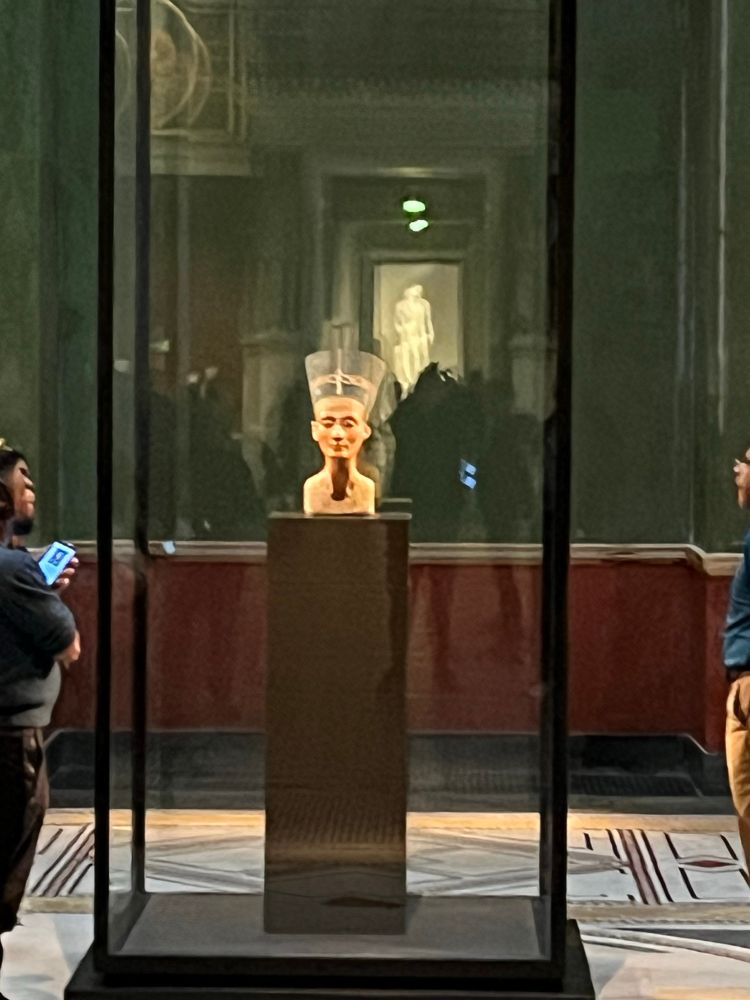 Bust of Nefertiti. Enclosed in glass sitting on a tall pedestal. 