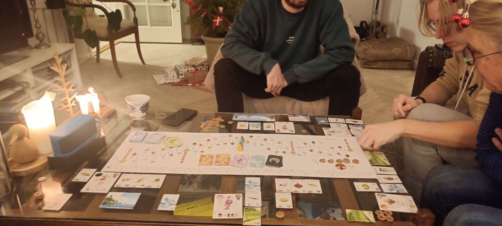 People playing the board game "Tokado" with candles in the background. 