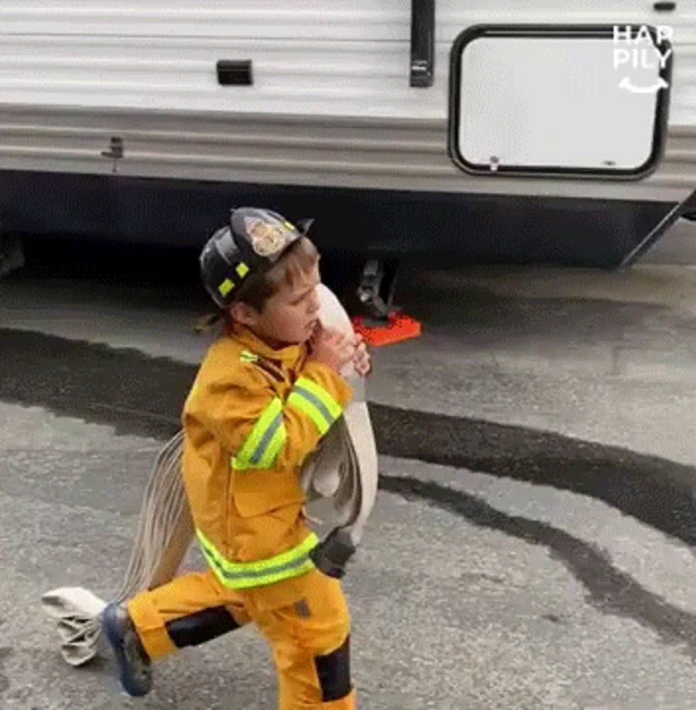 a young boy dressed as a fireman is holding a fire hose .