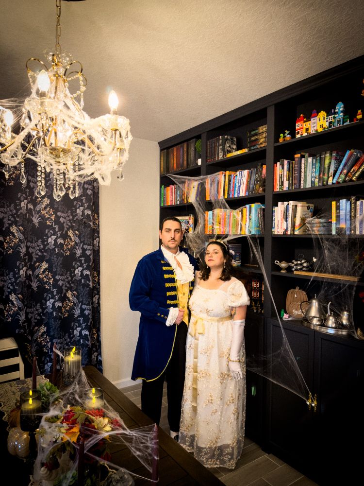 Wesley and his wife Gabriella wearing Victorian outfits for a Halloween tea party. They are both glaring at the camera in this picture 