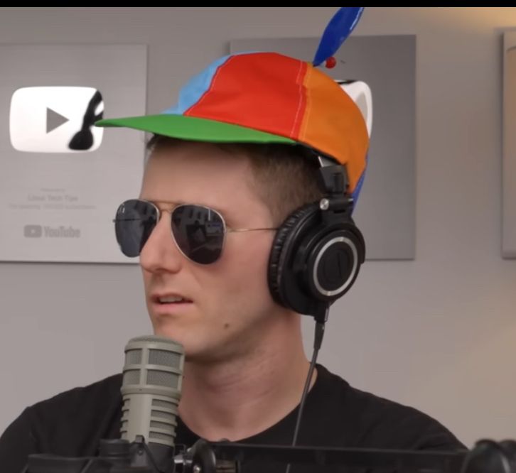 Linus Sebastian wearing a propeller hat, sunglasses, headphones and making a perturbed expression.