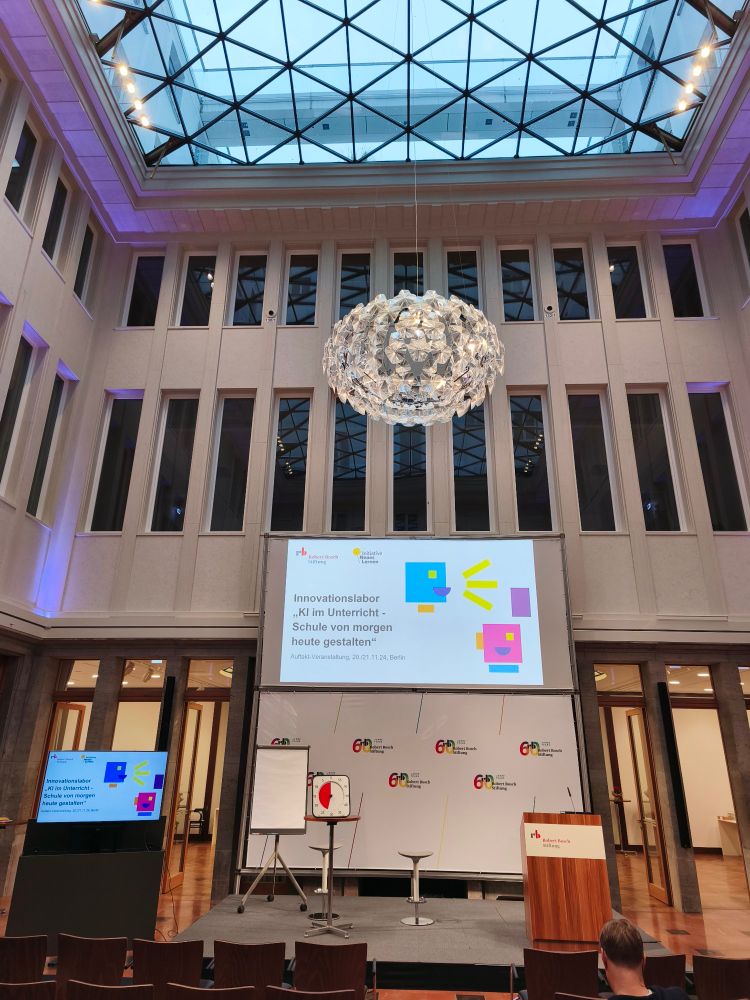 Leerer Saal in den Räumlichkeiten der Robert Bosch Stiftung. Auf der Leinwand der Titel des Projektes "KI Innovationslabor"