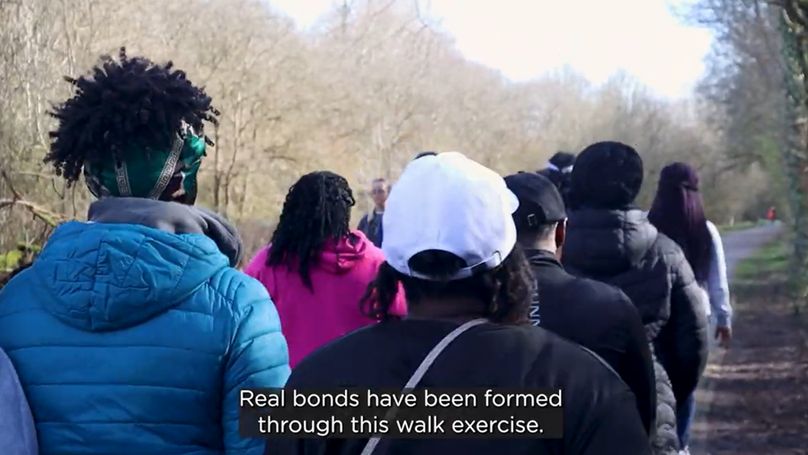 A group of women walk through a wintery park in warm clothes. Underneath reads the subtitle, "Real bonds have been formed through this walk exercise."

