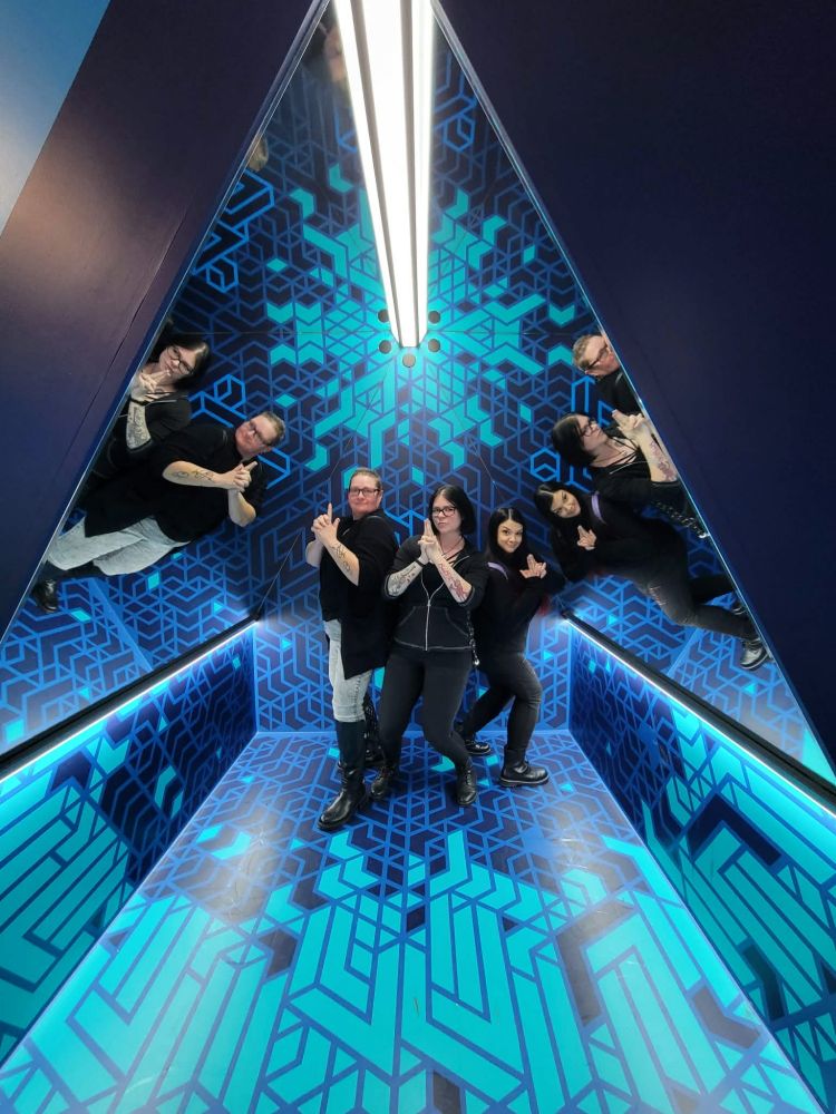 Charlie's Angel's pose with friends in a mirrored triangle room. It looks like I've entered the 90s music video liminal space.