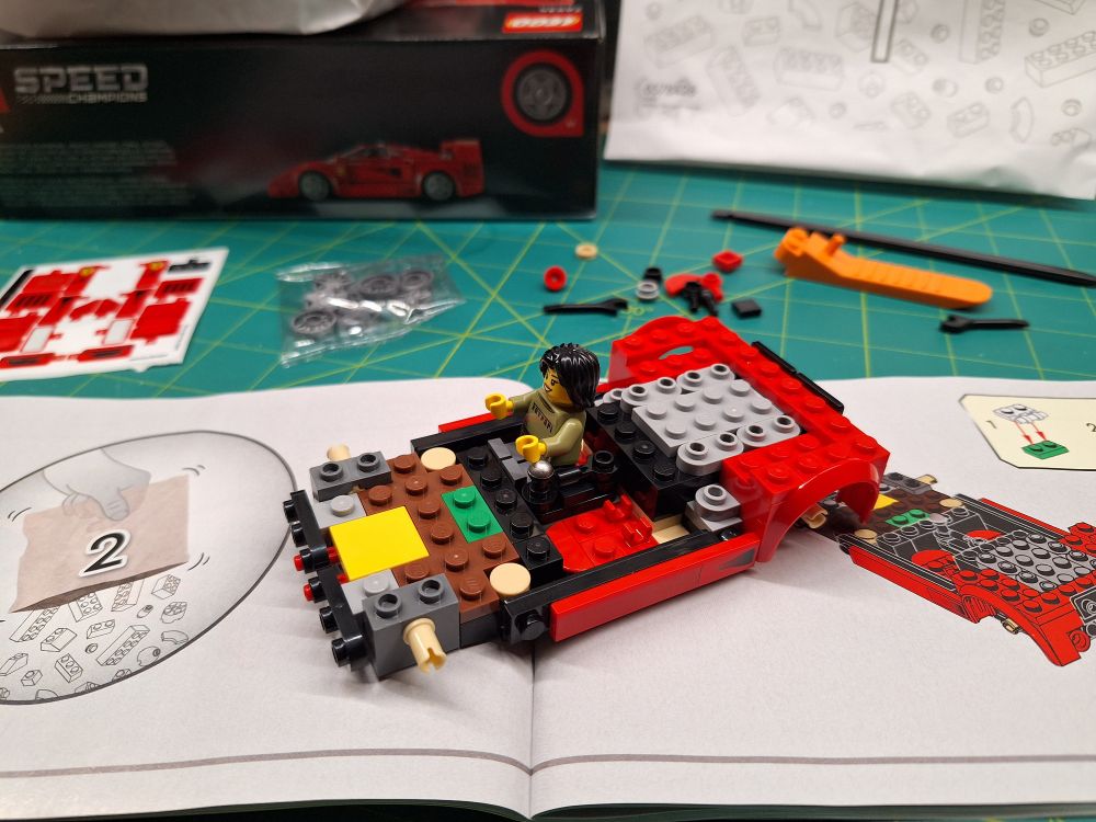 A 25% built Lego Ferrari car sitting on its build manual on the page where it tells you to open bag 2.