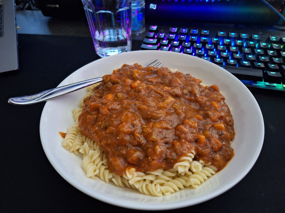 A large pasta bowl full of Fusilli pasta covered in chunky Bolognese sauce.