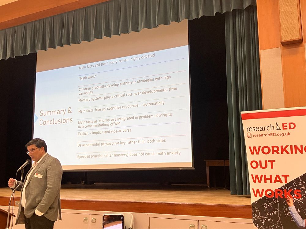 Dr. Ansari speaks, while a summary of his main points is on the slide behind him. 