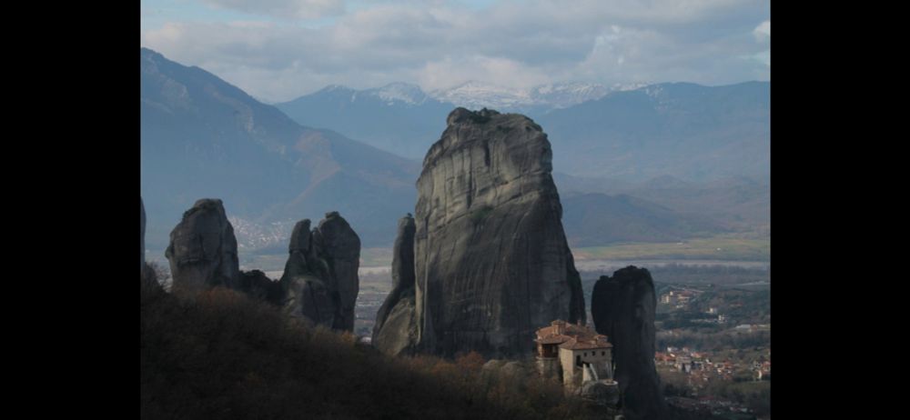 Piton rocheux avec montagnes en arrière plan et monastère en premier plan